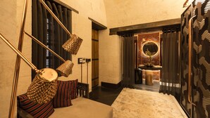 Un couloir avec un canapé, des coussins à motifs, une lampe suspendue et un miroir doté d’un cadre décoratif.
