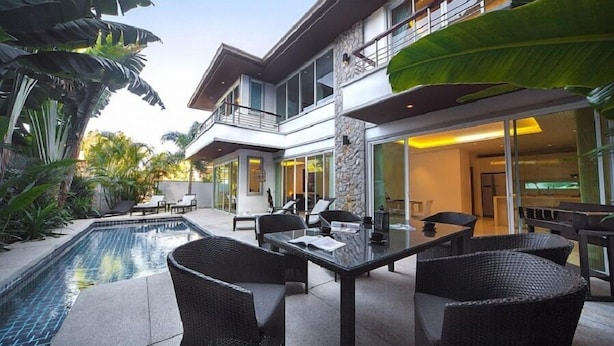 A modern two-story house with a swimming pool, outdoor seating, and large windows. - Villa Cheloni 3 Bedrooms (Kamala)