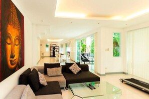 A modern living room with a sofa, a glass coffee table, and a treadmill.