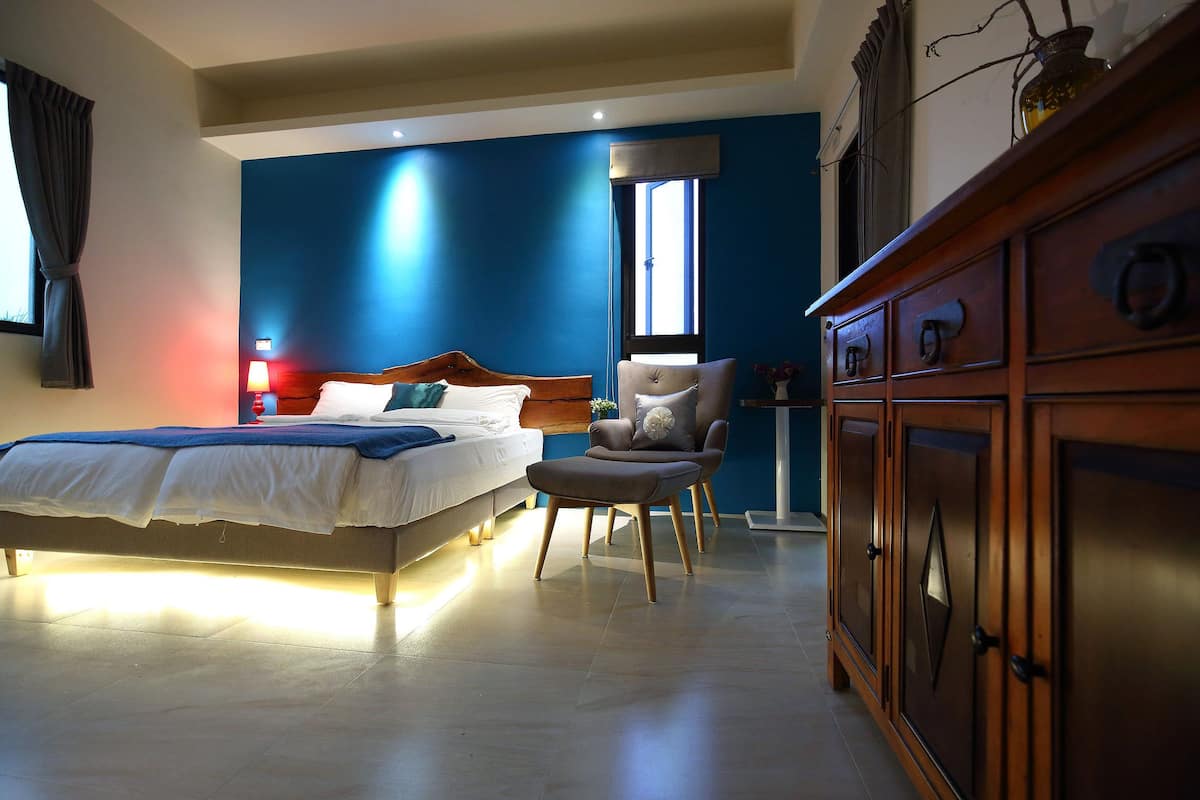 Un dormitorio con una cama, una silla y un armario de madera.
