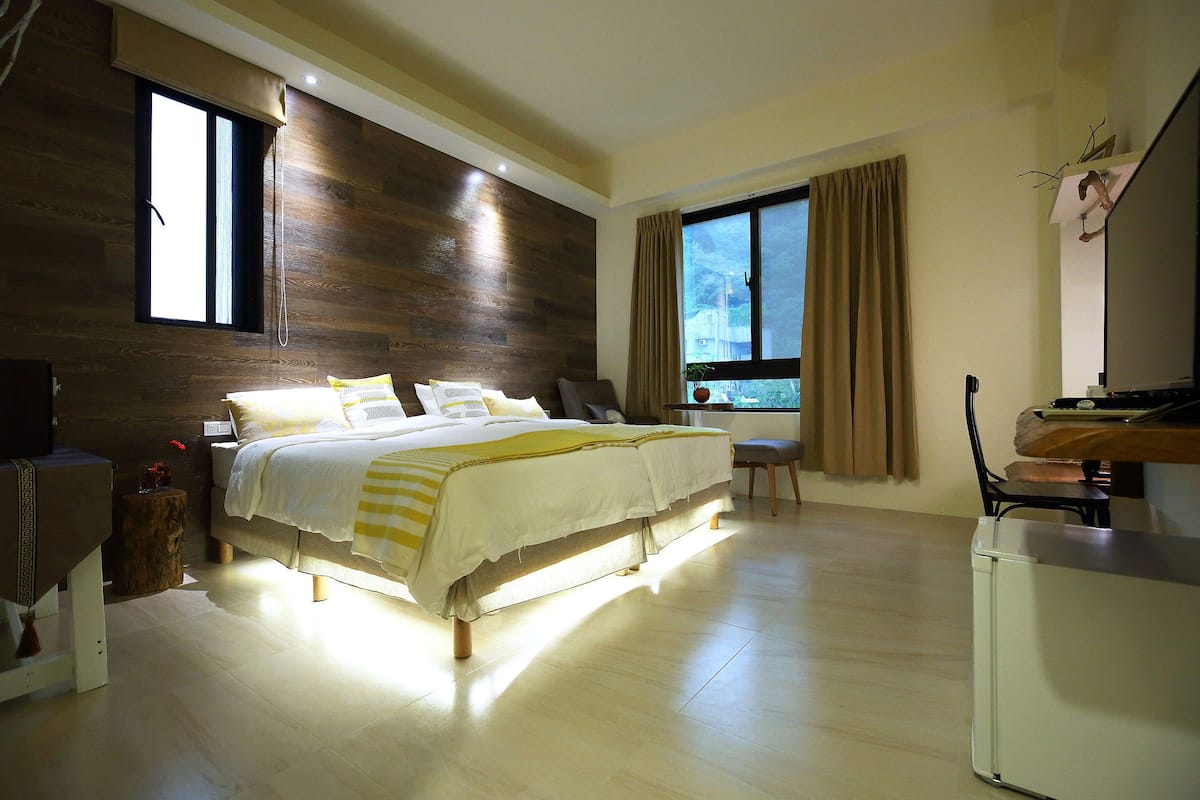 Un dormitorio moderno con una cama grande, un escritorio y una ventana con cortinas.