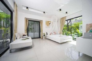 A modern bedroom with a bed, a sofa, a desk, and a large window. - Villa Kamala Regent 3-4 Bedrooms (Kamala)