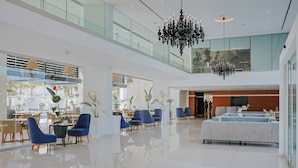 Eine geräumige Lobby mit hoher Decke, einem Kronleuchter und Sitzbereichen.
