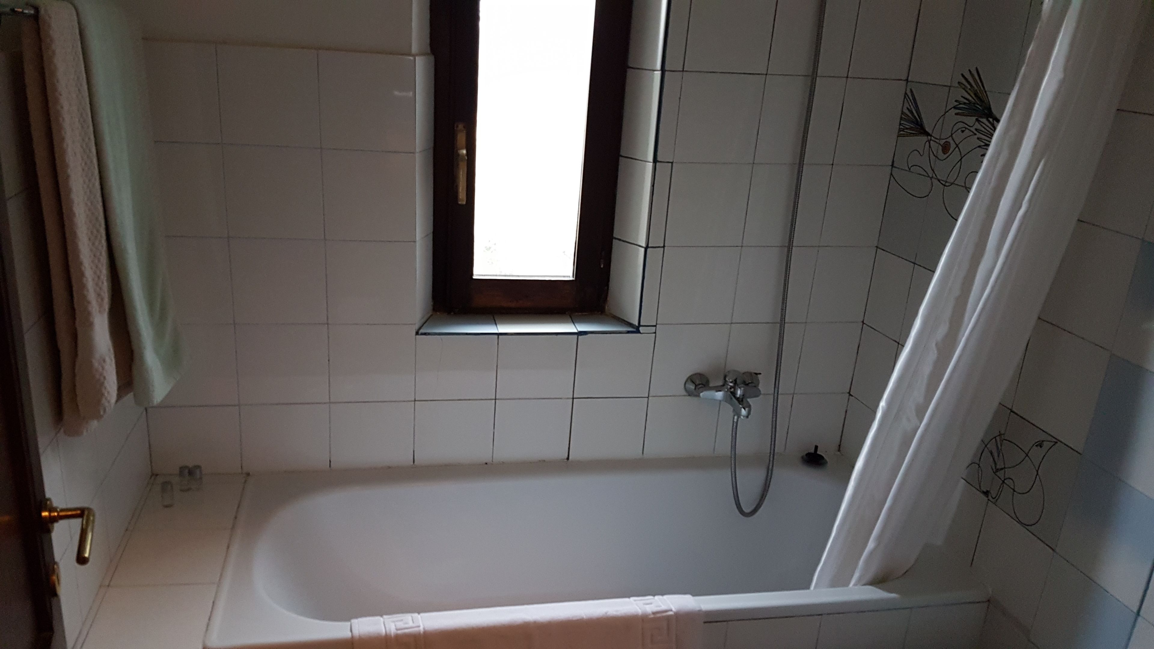 A bathroom with a bathtub, a window, and tiled walls.