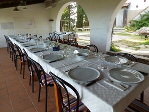 A long dining table set for a meal with chairs, a white tablecloth, and various tableware. - Albergo Montechiari (Palaia)