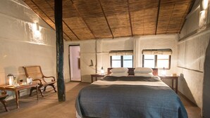 Ein Schlafzimmer mit einem Bett, einem Holztisch mit Stühlen, einem Fenster und einer Tür.