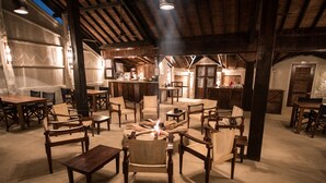 Ein rustikales Interieur mit Holzmöbeln, einem zentralen Feuerkorb und einer Küchenzeile im Hintergrund.