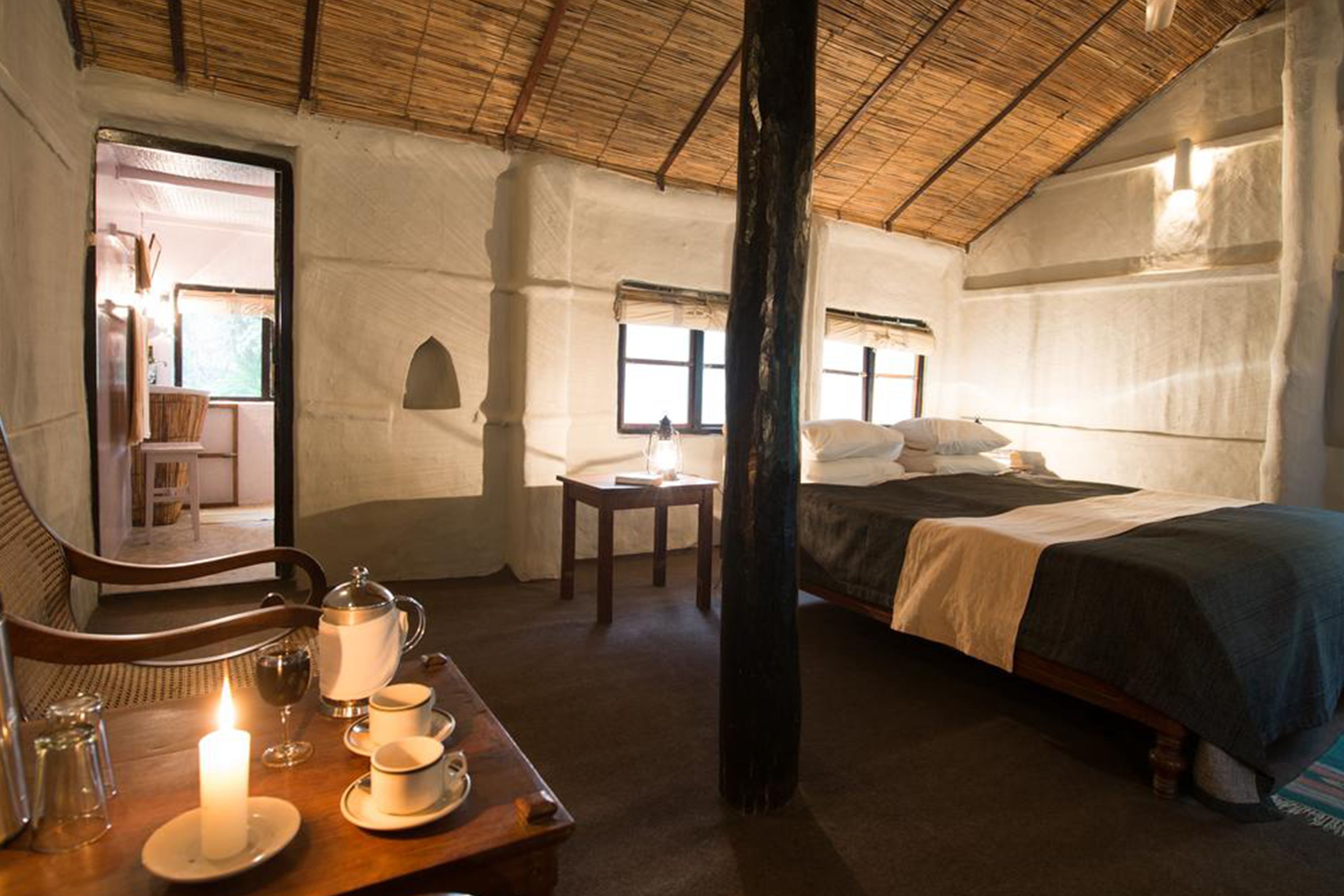 Een gezellige kamer met een bed, een tafel met een kaars en een stoel.