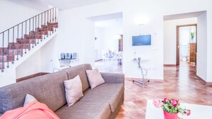 A modern living room with a grey sofa, a red blanket, and a red vase with flowers. - Maison Palazzo Correale (Sorrento)