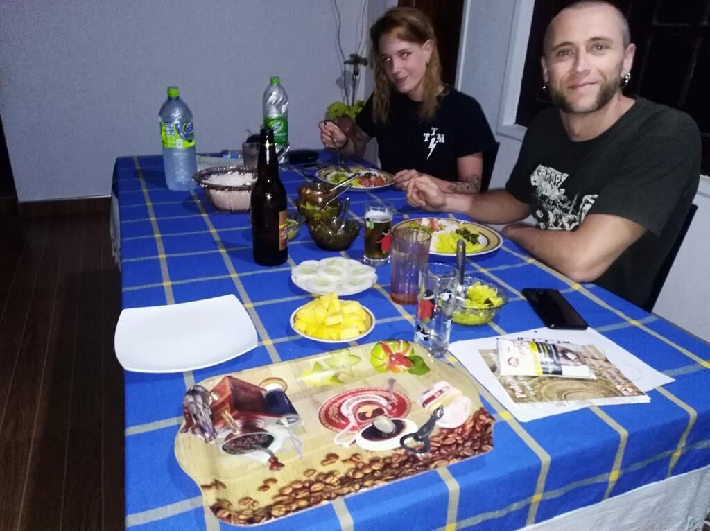 A dining table with a blue tablecloth, plates of food, bottles, and a smartphone.