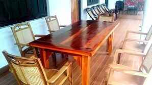 Una mesa de comedor de madera con seis sillas, piso de madera y una ventana con un persiano verde.