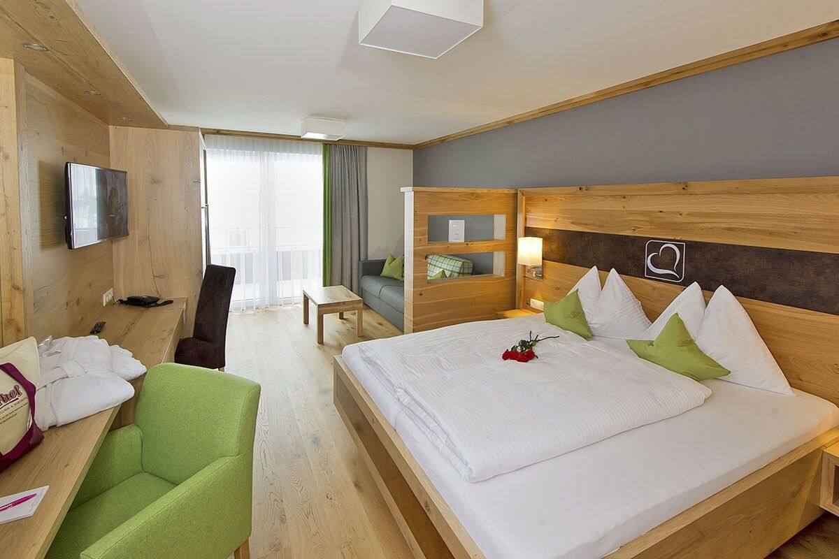 Une chambre d’hôtel comprenant un lit, un bureau avec une chaise, un téléviseur fixé au mur et un balcon avec vue.
