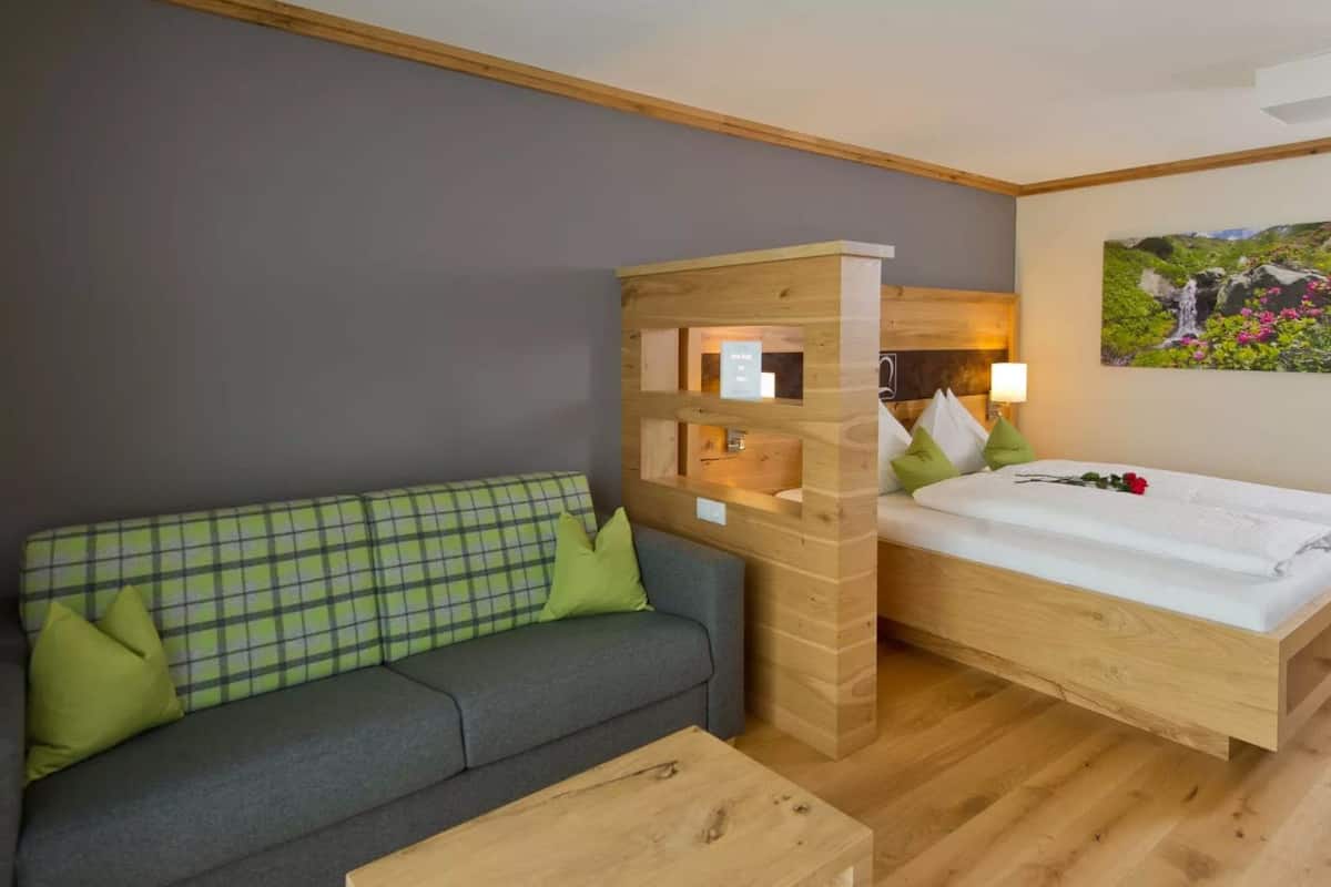 Une pièce avec un lit en bois, un canapé gris et une table basse en bois.