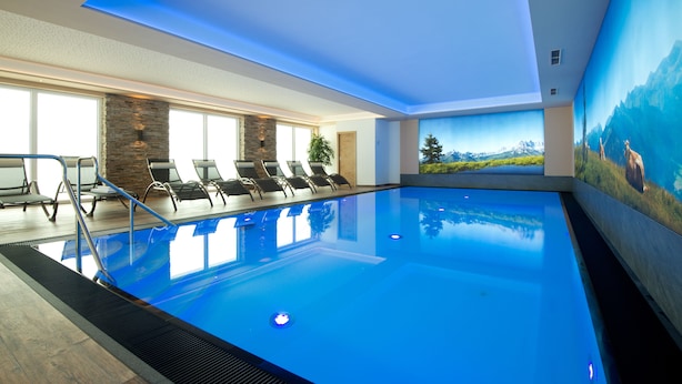 Une piscine intérieure offrant une vue dégagée sur les montagnes grâce à une grande baie vitrée.
