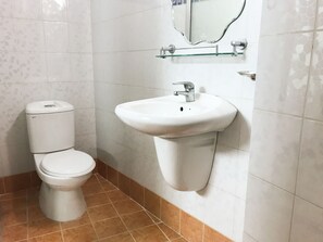 Une salle de bain avec des toilettes, un lavabo et un miroir.