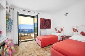 Une chambre d’hôtel avec deux lits, un balcon avec vue et un grand tableau représentant des roses.