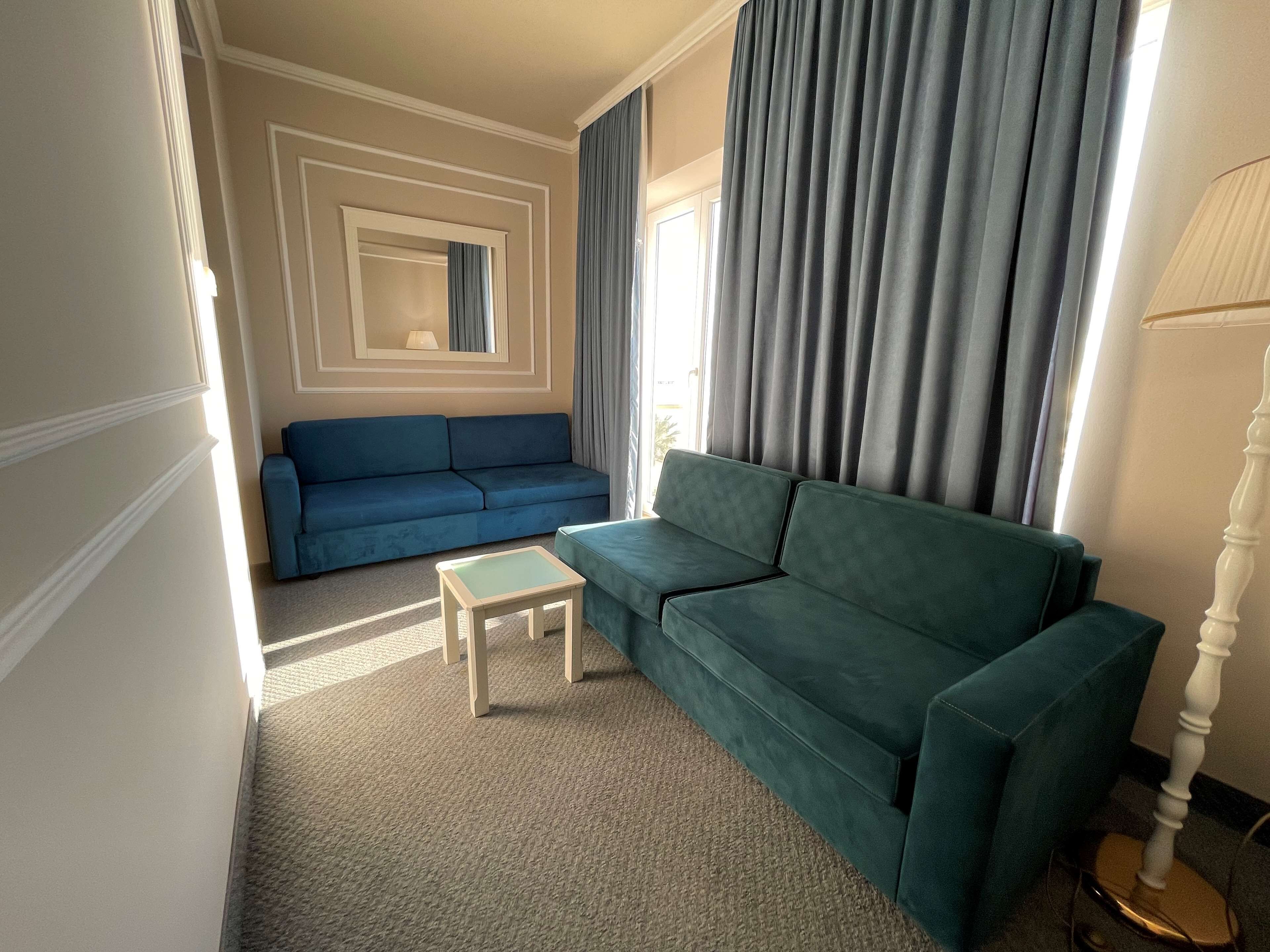 Una sala de estar con un sofá azul, un sofá verde y una mesita.
