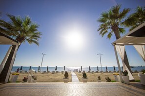 Aan een privéstrand, wit zand, ligstoelen, parasols