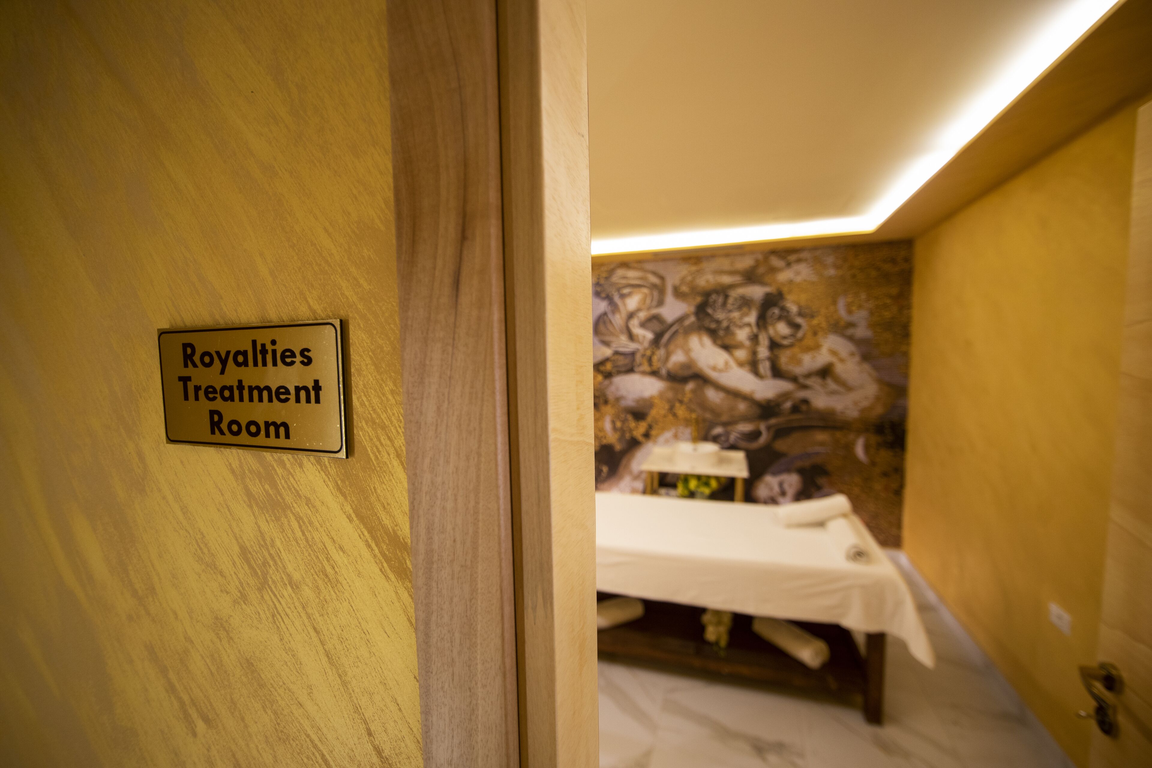 Una habitación con un cartel que dice 'Royalties Treatment Room' y una cama con sábana blanca.