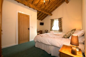 Un dormitorio con techo de madera, una cama con lámpara, una ventana con cortinas y una puerta.