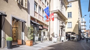 A hotel named "HOTEL SAN CARLO" with a signboard, potted plants, and flags. - Hotel San Carlo (Lugano)