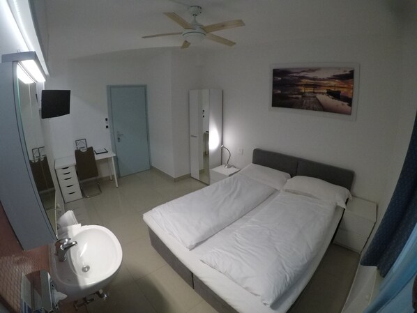 Una habitación de hotel con cama, mesita de noche, lámpara y un cuadro en la pared.