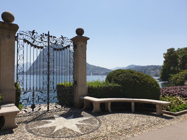 A stone gate with a star-patterned mosaic floor, leading to a scenic view of a lake and mountains. - Hotel San Carlo (Lugano)