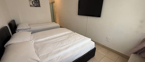 Une chambre à coucher avec un lit, un téléviseur fixé au mur et une porte donnant sur une autre pièce.