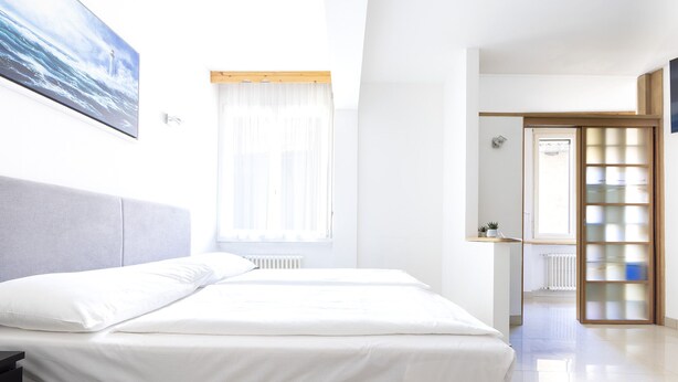 A modern hotel room with a bed, a bedside table, a window with curtains, and a view of the outside. - Hotel San Carlo (Lugano)