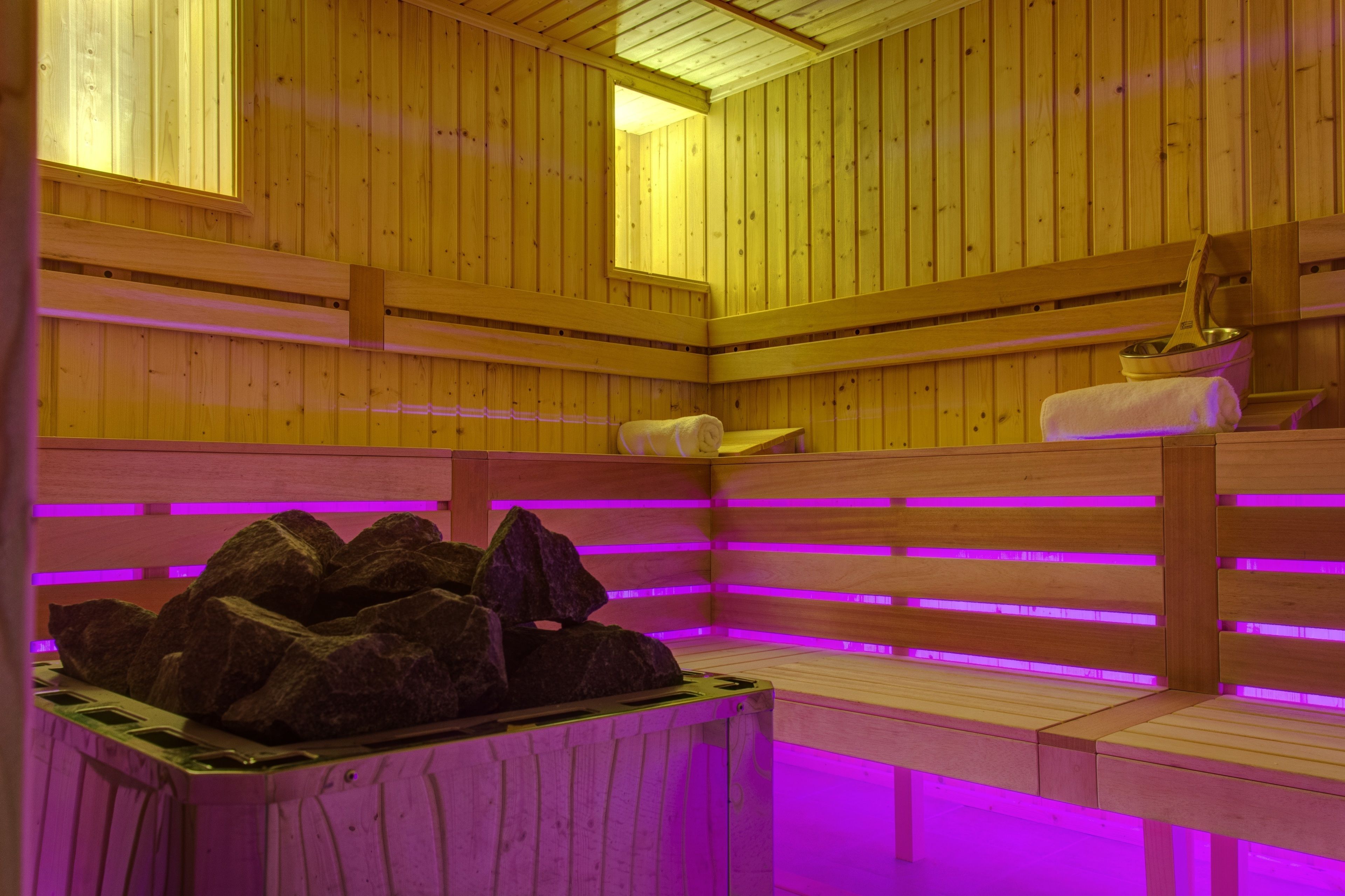 A wooden sauna with benches and a rock feature.