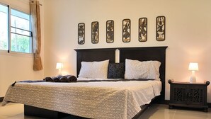 Une chambre à coucher comprenant un lit, deux tables de chevet, une fenêtre avec des rideaux et des œuvres d’art murales.