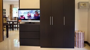 Un salon moderne avec une armoire en bois foncé, un téléviseur et une petite poubelle.