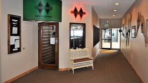 A hallway with a Double Diamond Restaurant sign, a bench, and framed pictures on the wall.