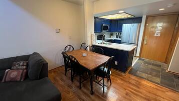 Een knus woongedeelte met een eethoek, kitchenette en een bank.