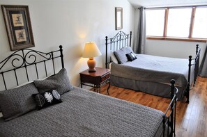 Une chambre avec deux lits, une table de chevet avec une lampe et une fenêtre avec des rideaux.
