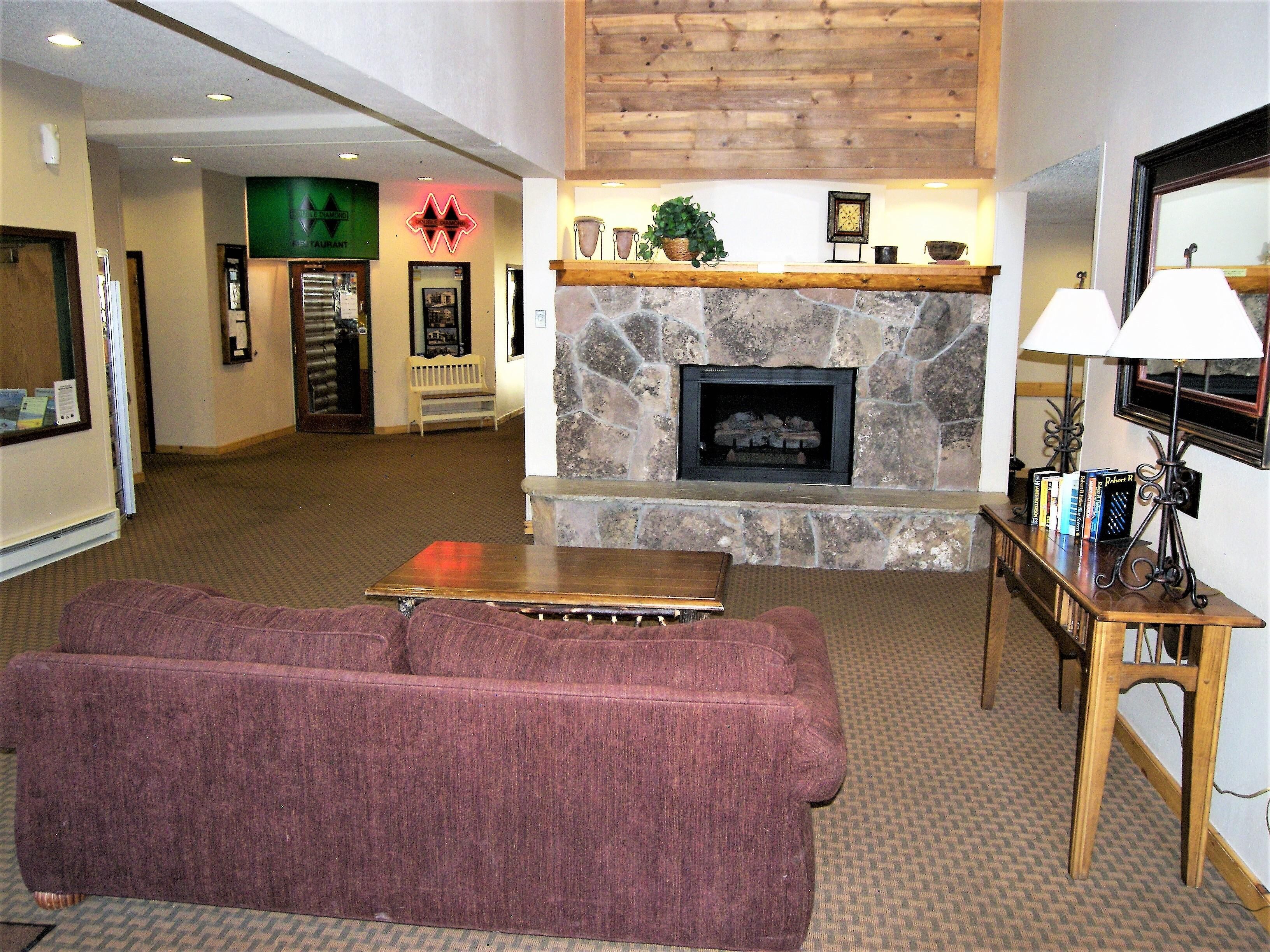 A living room with a stone fireplace, a wooden coffee table, and a red sofa.
