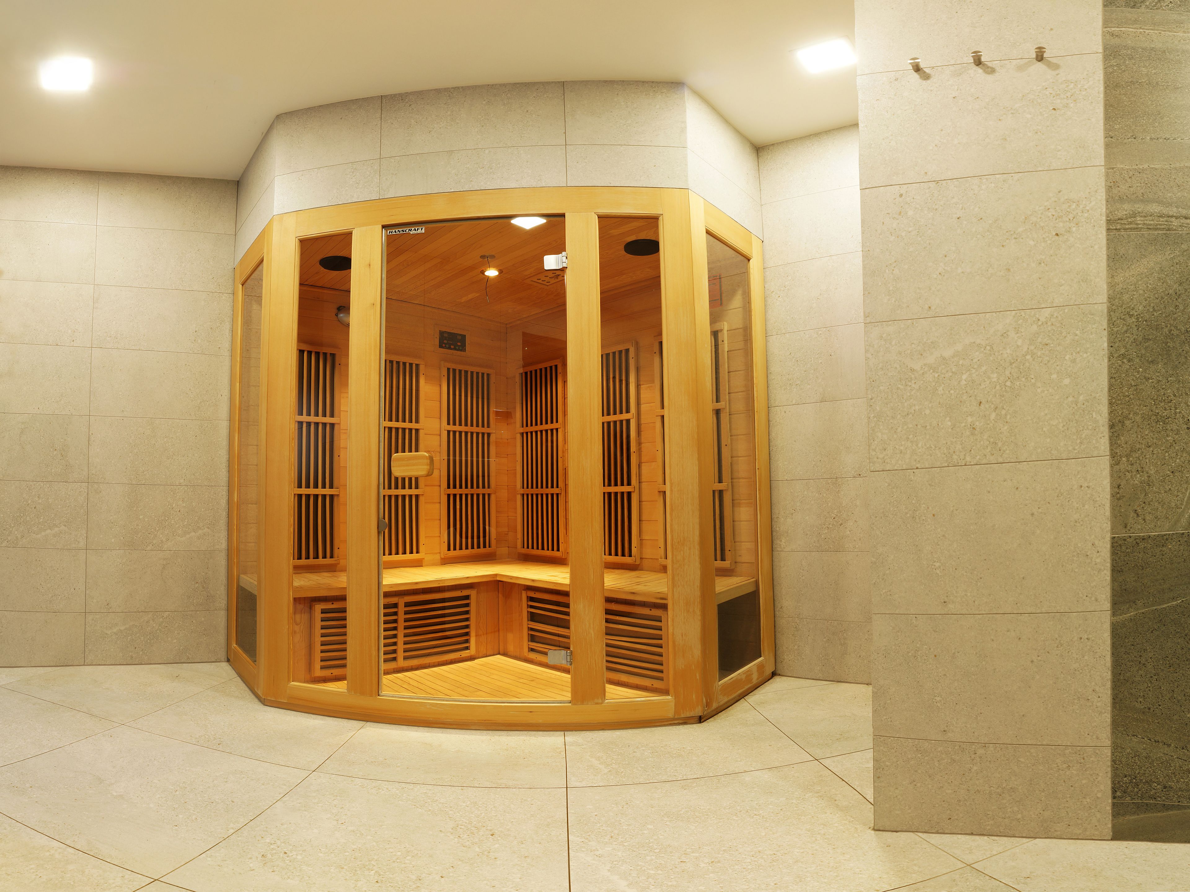 A wooden sauna with a curved design, tiled floor, and a ceiling light.
