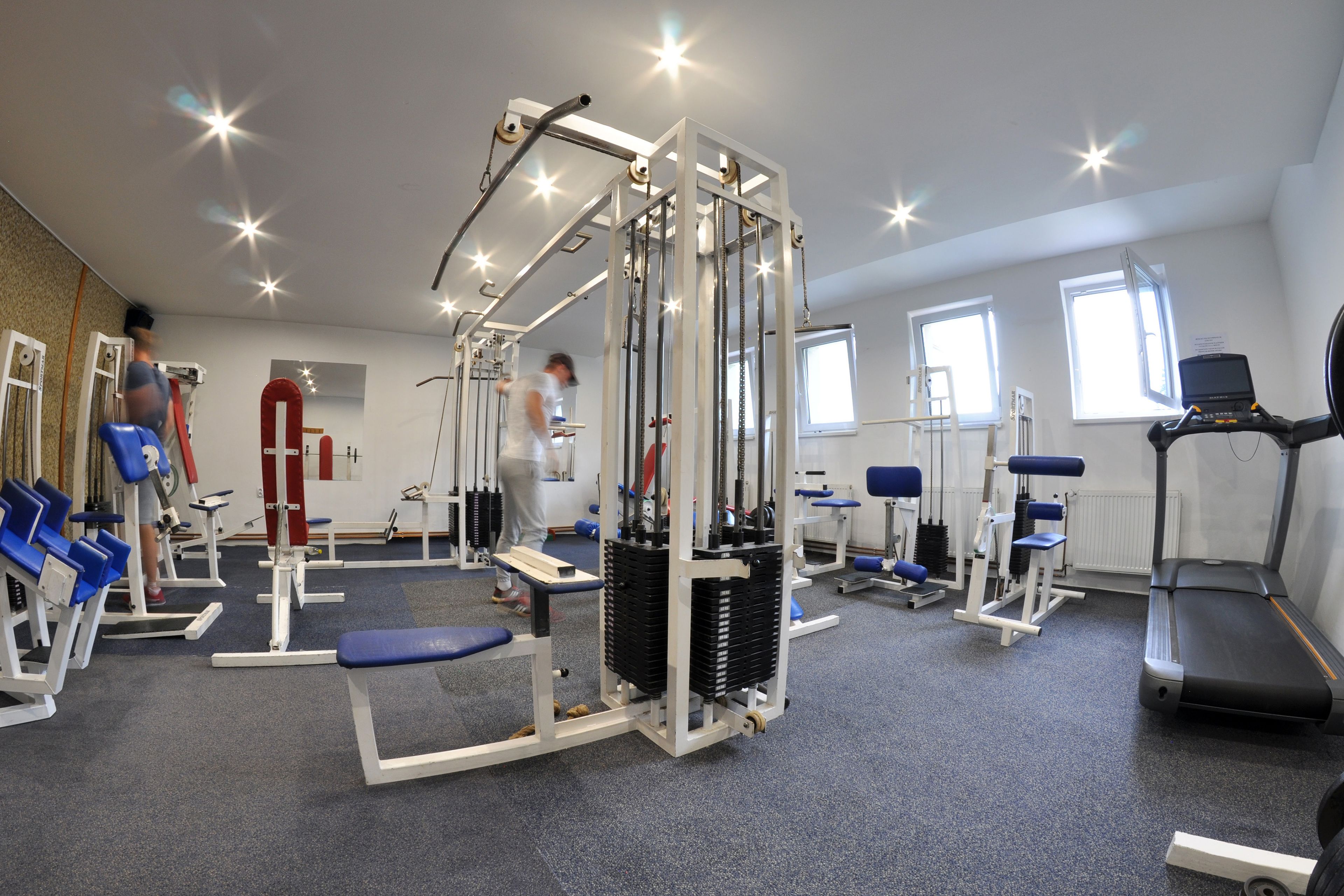 A gym with various exercise equipment, including a treadmill, weight machines, and benches.