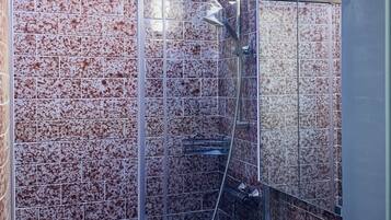 A bathroom with a glass-enclosed shower, a white sink, and a tiled wall.