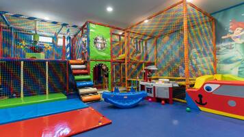 Un área de juegos con una red de escalada, toboganes y una cocina de juguete.