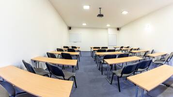 A classroom with desks and chairs arranged in rows, a projector, and a whiteboard.