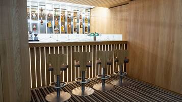 A bar area with multiple stools, a counter with a display of bottles, and a patterned floor.