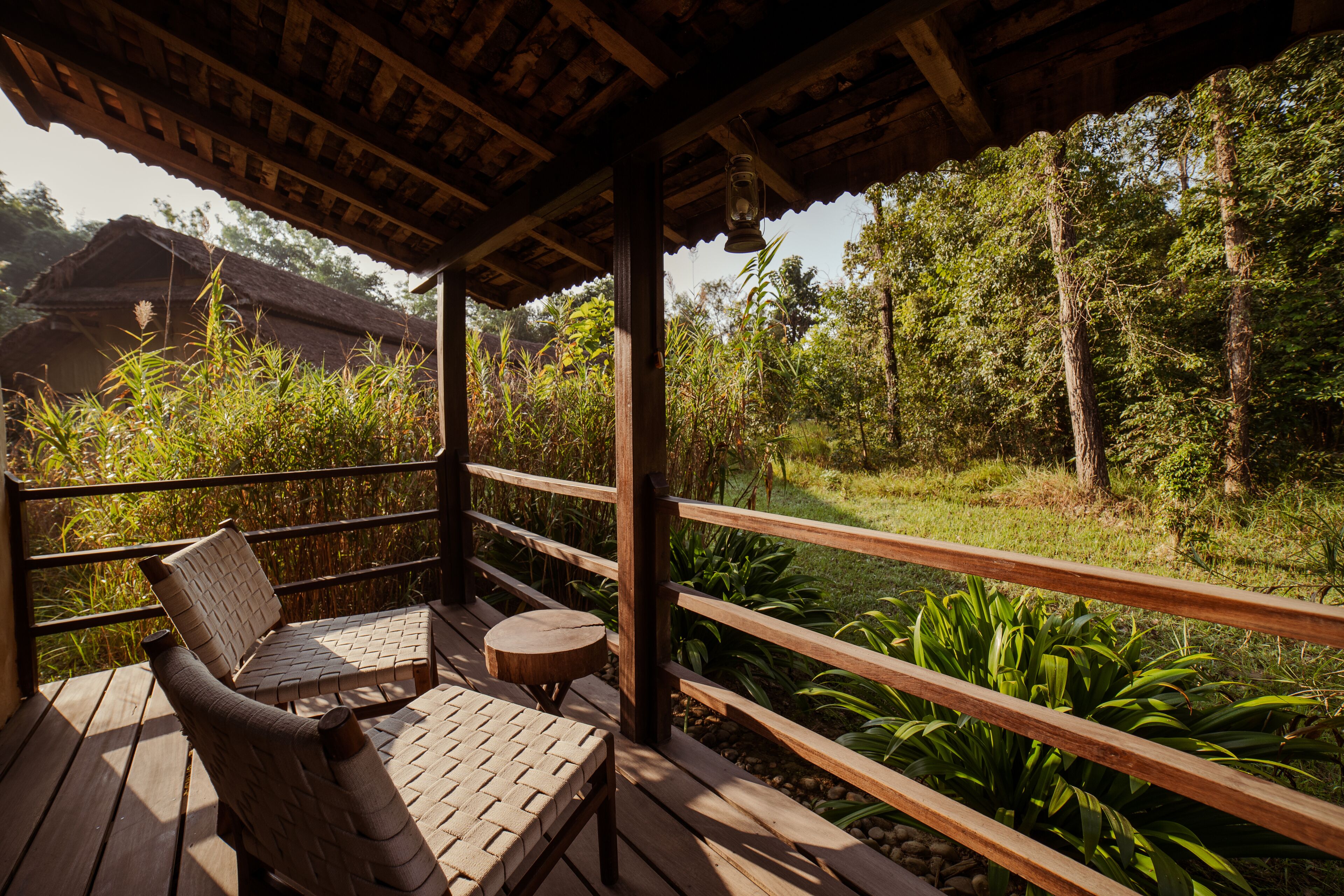 A wooden deck with a thatched-roof structure, two wicker chairs, and a small round table.