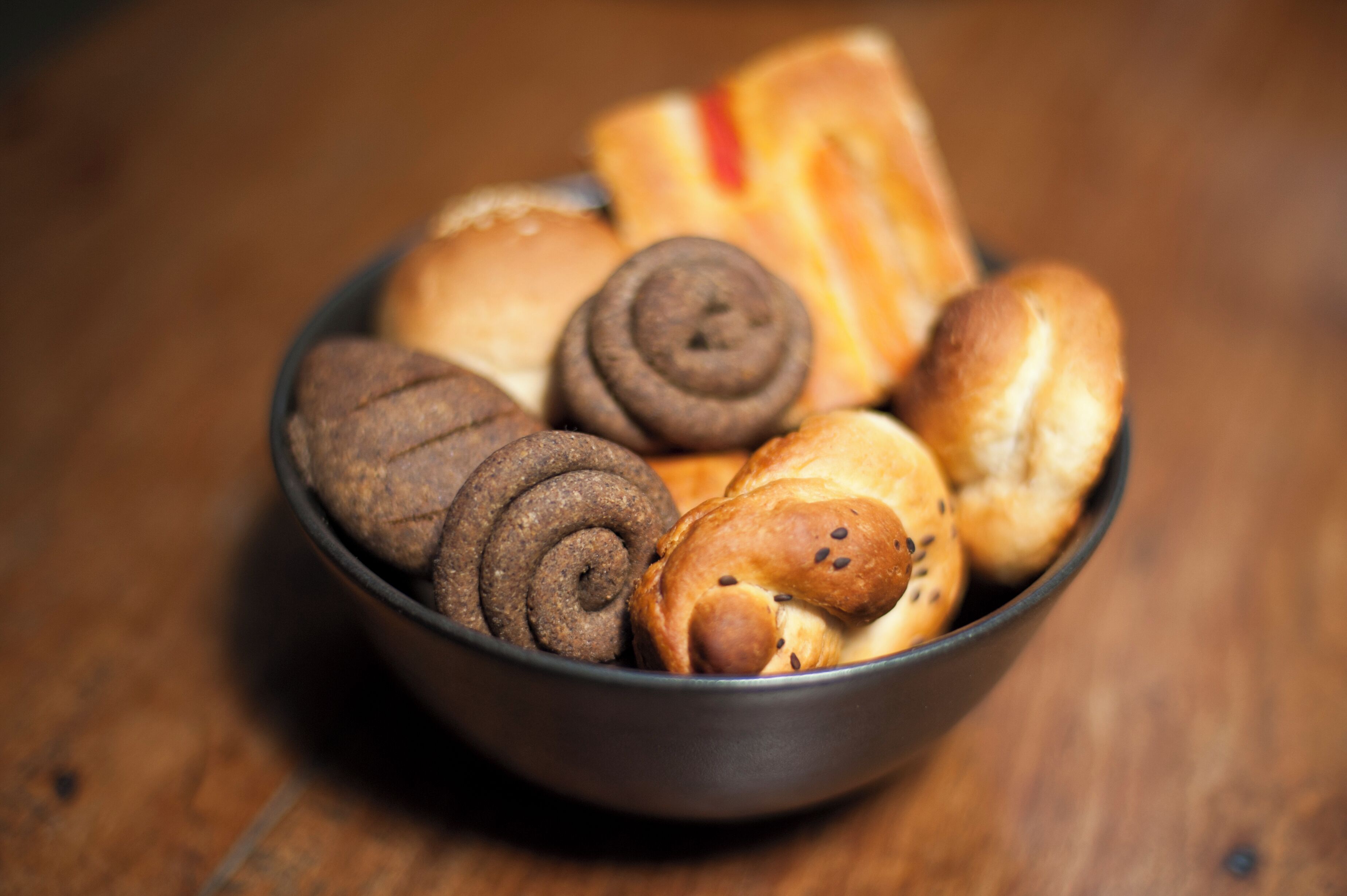 Un bol con distintos tipos de pan y pastelería.