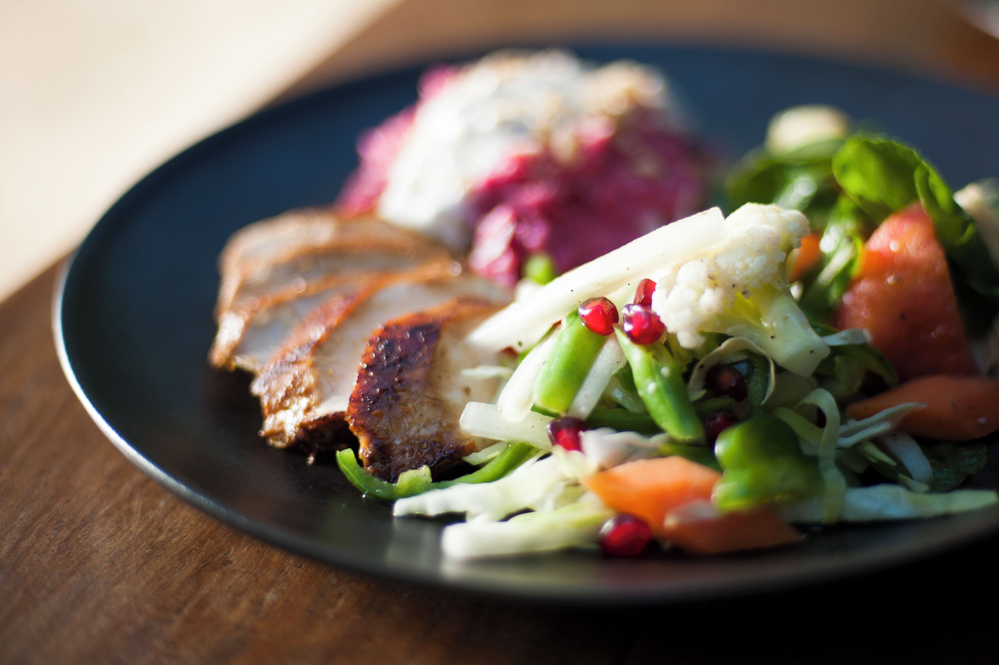 A plate with sliced meat, vegetables, and a side salad.