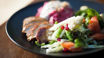 A plate with sliced meat, vegetables, and a side salad.