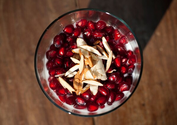 A bowl containing pomegranate seeds and sliced almonds.