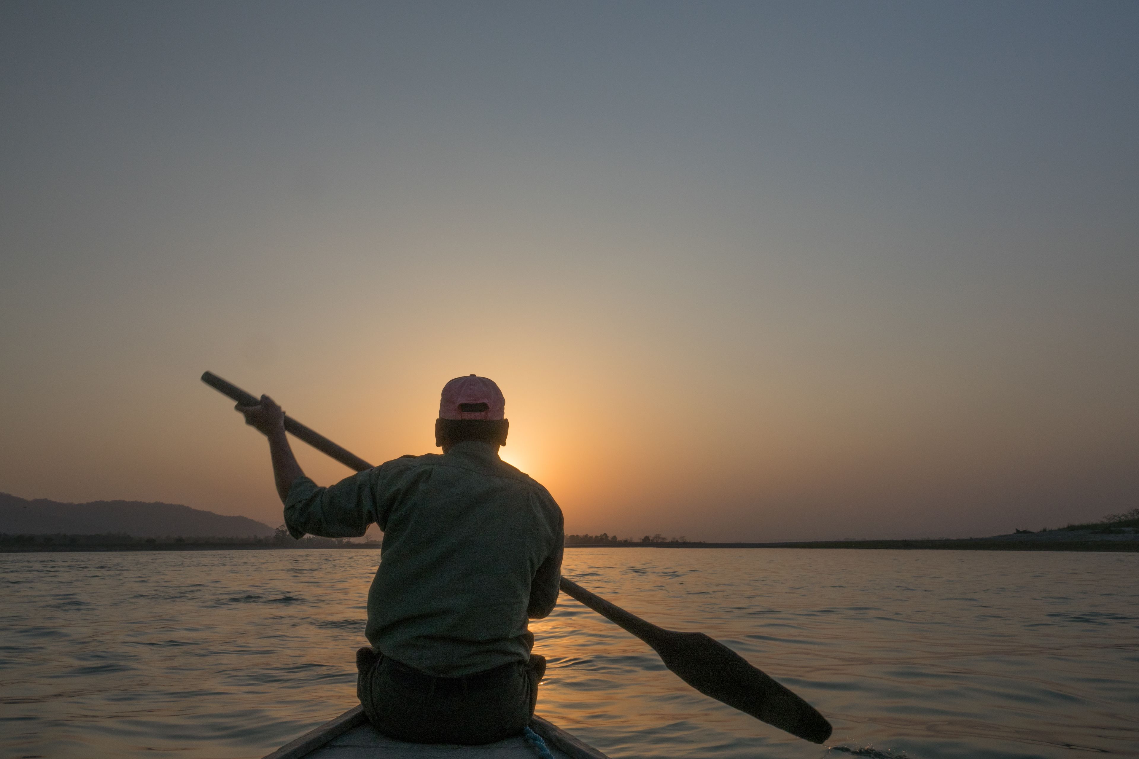A person rowing a boat during sunset.