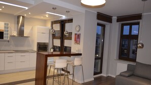 Een moderne keuken met witte kasten, een roestvrijstalen afzuigkap en een eethoek met een houten kookeiland en barstoelen.