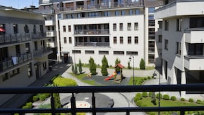 Een meerlaags woongebouw met balkons, een speeltuin en een aangelegde binnentuin.